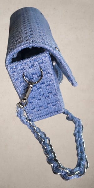 Seitenansicht der Valentina Tasche – geöffnete Klappe zeigt das Innenfach, silberfarbener Karabiner und Canvas-Kettenriemen in Hellblau.