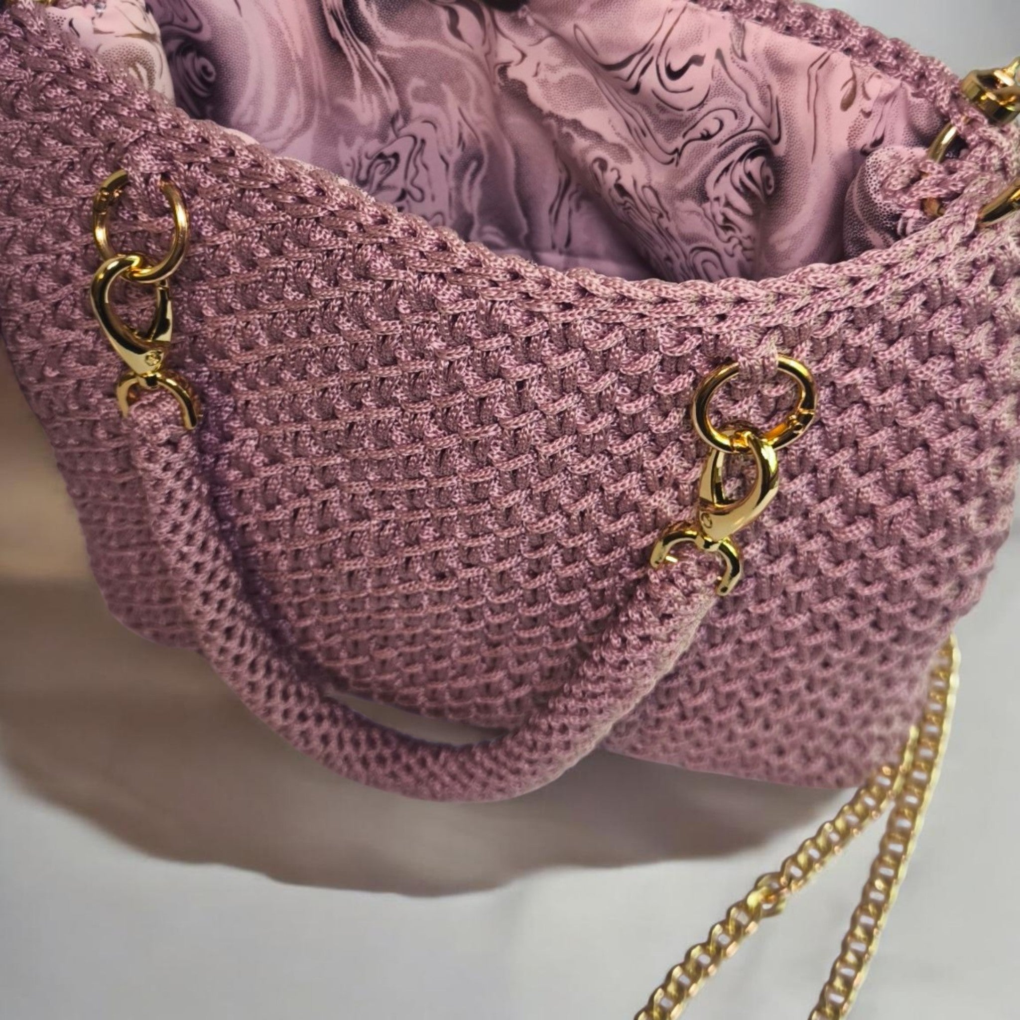 •	100 % Handarbeit: Jede Tasche ist ein mit Liebe gefertigtes Unikat.
•	Exklusives Branding: Hochwertiges, goldenes „Cora Fashion“-Metall-Label auf der Front.
•	Luxuriöse Details: Goldfarbene Karabiner, Ringe, ein stilvoller Fransen-Anhänger und eine elegante Schulterkette.
•	Wandelbarer Style: Tragbar als klassische Handtasche an dem festen Henkeln oder lässig über der Schulter.
•	Edles Innenleben: Wunderschön gemustertes Futter im kunstvollen Marmor-Design (Lila/Rosa-Nuancen).