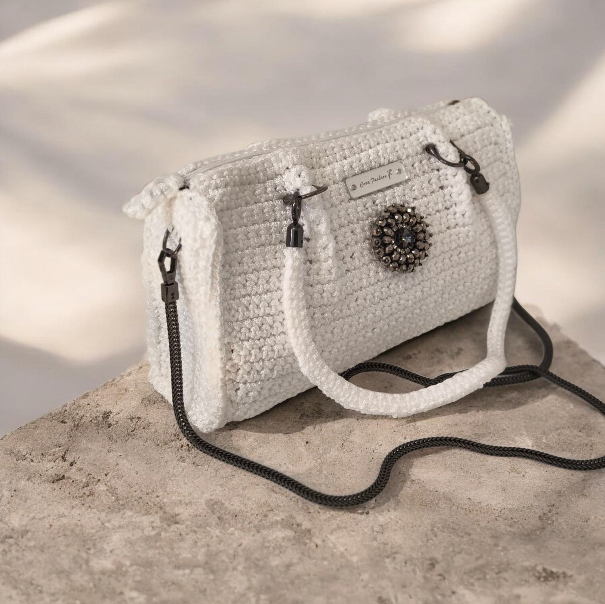  Handgefertigte Eleganz in purem Weiß.
Diese edle Häkeltasche ist ein absoluter Blickfang und vereint moderne Handwerkskunst mit luxuriösen Details. Gehäkelt aus hochwertigem Polyester-Garn, besticht die Tasche durch ihr dichtes, strukturiertes Maschenbild. Das Material sorgt dafür, dass die Tasche besonders formstabil, strapazierfähig und langlebig bleibt.
